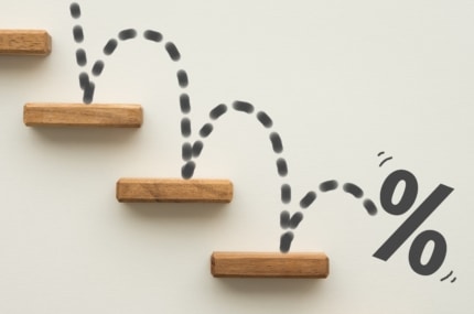 Houten blokjes als dalende treden met stippellijn die naar beneden springt en een procentteken, symbool voor dalende percentages of afname.