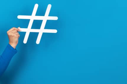 Arm die door een blauwe muur breekt en een groot hashtag-symbool vasthoudt.