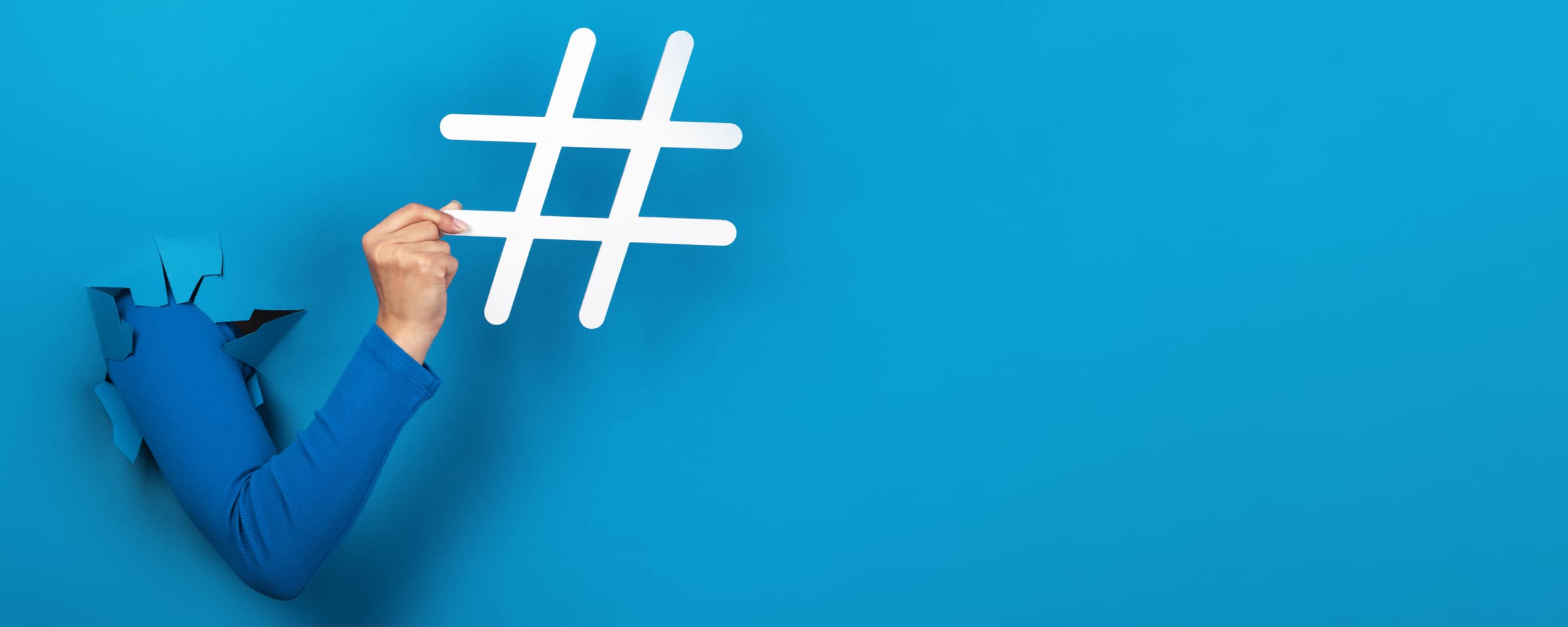 Arm die door een blauwe muur breekt en een groot hashtag-symbool vasthoudt.