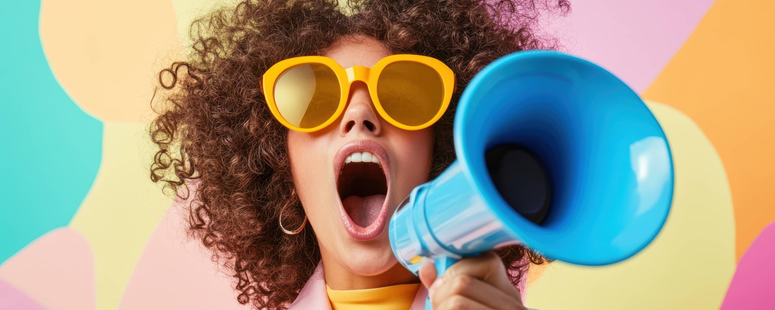 Vrouw met krullend haar en gele zonnebril roept door een blauwe megafoon tegen een kleurrijke achtergrond.