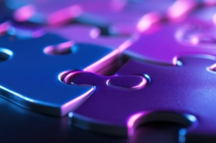 Close-up van in elkaar passende puzzelstukken met paarse en blauwe neonverlichting.